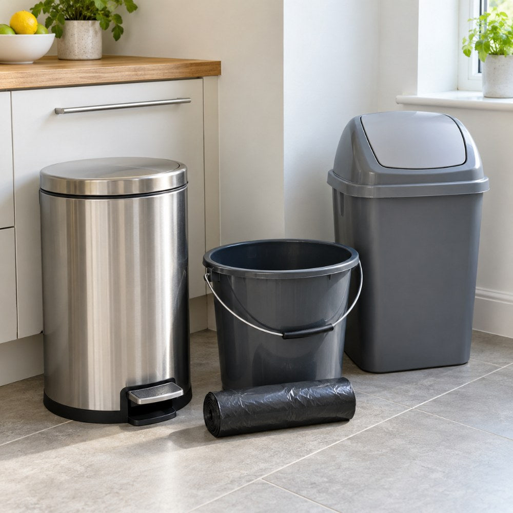A pedal bin, a roll of bin liners, a plastic bucket and a swing bin in a clean kitchen corner