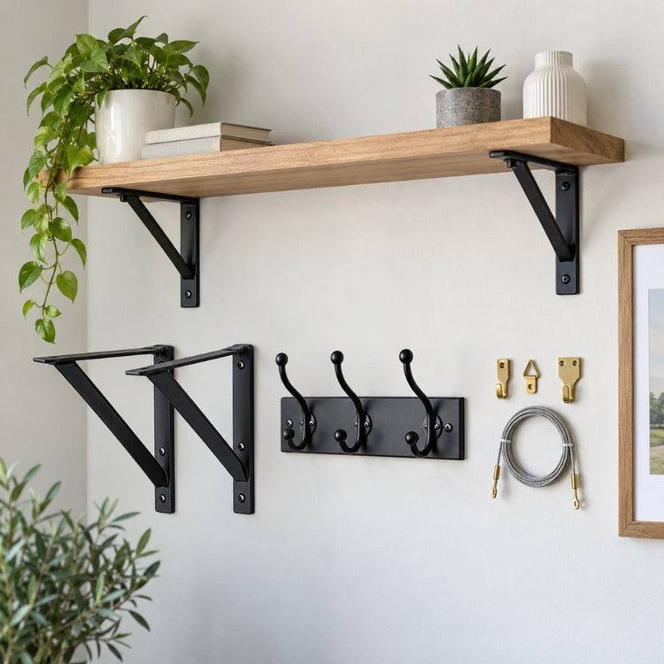 Black metal shelf brackets, coat hooks, picture hooks with wire and a wall-mounted shelf on a pale painted wall